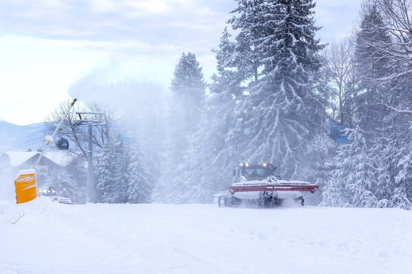 Snow groomer snowcat ratrack machine preparing ski road slope for alpine skiing, winter resort Bansko, Bulgaria