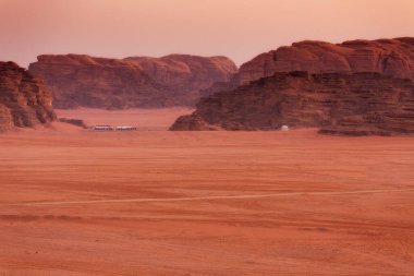 Wadi Rum, Jordan. Turuncu kum çölü manzarası ve şafak vakti kaya dağları, çadırlar.