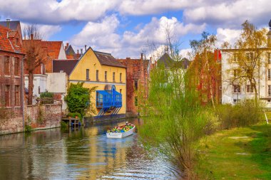 Gent, Belçika - 12 Nisan 2016: Kanal boyunca eski evler ve turist dolu tekneler popüler turizm beldesi Gent