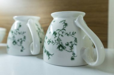 Açılmış beyaz ve ahşap mutfak dolabında baş aşağı duran temiz kupalar, depo dolabı.