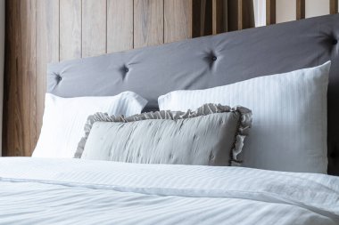 Rahat beyaz ve gri yastıklar yatağın üzerinde, misafir konaklama hazır.