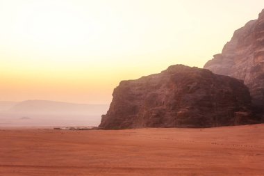 Wadi Rum, Jordan. Turuncu kum çölü manzarası ve şafak vakti kaya dağları, çadırlar.