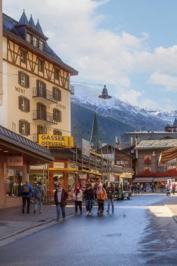 Zermatt, İsviçre - 7 Ekim 2019: Ünlü İsviçre kayak merkezi, renkli geleneksel evler, dağlar ve insanların ana cadde manzarası