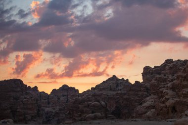 Küçük Petra arkeoloji sahasında kumtaşı kayaları olan günbatımı turuncu gökyüzü manzarası, Ürdün