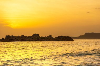 İnanılmaz plaj altın gün batımı turuncu gökyüzü, taş kayalar arka plan, kopyalama alanı