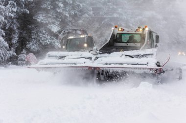 Bansko, Bulgaria - January 21, 2024: Snow groomer snowcat ratrack machines preparing ski slope for alpine skiing, winter resort clipart