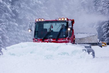 Bansko, Bulgaria - January 21, 2024: Snow groomer snowcat ratrack machine preparing ski slope for alpine skiing, winter resort clipart