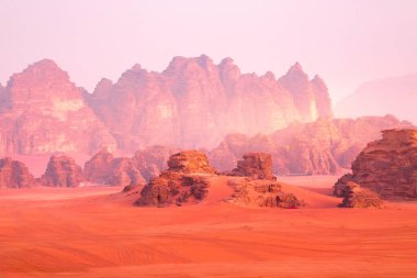 Wadi Rum, Jordan. Turuncu kum çölü manzarası ve şafak vakti Jabal Al Qattar dağları.