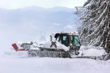 Bansko, Bulgaria - January 21, 2024: Snow groomer snowcat ratrack machine preparing ski slope for alpine skiing, winter resort clipart