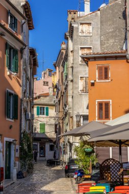 Rovinj, Hırvatistan - 23 Eylül 2024: Tarihi eski kentte renkli evleri ve kafesi olan cadde