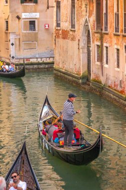 Venedik, İtalya - 30 Eylül 2024: Gondolcu eski şehrin kanalında bir gondolda