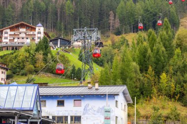 Ortisei, Italy- 26 Eylül 2024: Mont Seuc teleferik istasyonu ve kırmızı kulübeleriyle Dolomites 'teki Alp köyünün yaz manzarası
