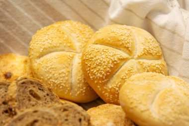 Ekmek sepetinde susamlı hamburgerlerin üst görüntüsü, kahvaltı için taze pişmiş.