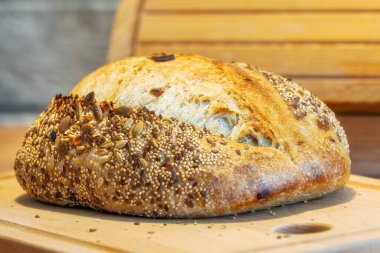 Mutfak masasında ev yapımı taze ekmek. Ekşi buğday ekmekli çavdar ekmeği. Tohumlar yakından görülüyor.