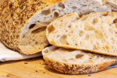 Ev yapımı taze ekmek ve mutfak masasında dilimler. Ekşi buğday ekmekli çavdar ekmeği. Tohumlar yakından görülüyor.