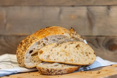 Ev yapımı taze ekmek ve mutfak masasında dilimler. Ekşi buğday ekmekli çavdar ekmeği. Tohumlar yakından görülüyor.
