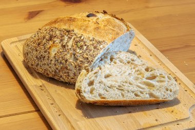 Ev yapımı taze ekmek ve mutfak masasında dilimler. Ekşi buğday ekmekli çavdar ekmeği. Tohumlar yakından görülüyor.
