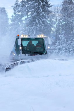 Bansko, Bulgaria - January 21, 2024: Snow groomer snowcat ratrack machine preparing ski slope for alpine skiing, winter resort clipart