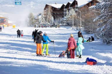Bansko, Bulgaristan - 20 Aralık 2023: Gondol kaldırma kulubeleri, dağ zirveleri manzaralı Bulgar kış kayak merkezi manzarası ve daha düşük istasyon yakınlarındaki kayakçılar