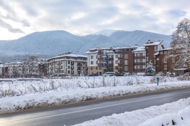 Bansko, Bulgaristan - 17 Ocak 2025: Bulgar kayak beldesinde kışın sokak manzarası, evler ve Pirin Dağı zirveleri