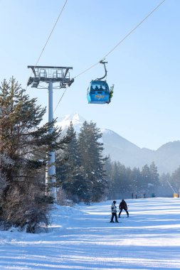 Bansko, Bulgaristan - 17 Ocak 2025: Gondol kaldırma kulubeleri, Pirin dağı zirveleri, yamaç ve kayakçıları olan Bulgar kış kayak merkezi manzarası