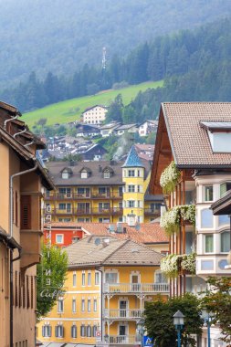 Ortisei, Italy- 26 Eylül 2024: Dağları ve renkli evleri olan Dolomitlerdeki Alp köyünün yaz manzarası