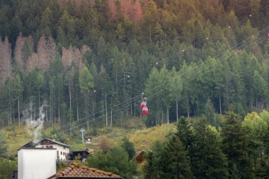 Ortisei, Italy summer view in alpine village in Dolomites with Mont Seuc cable car red cabins and houses clipart