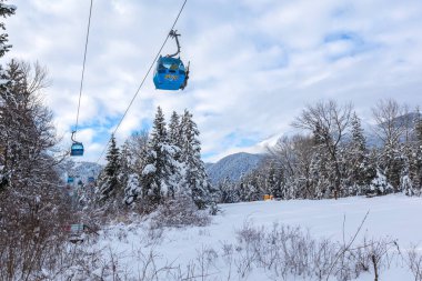 Bansko, Bulgaristan - 17 Ocak 2025: Kayak teleferiği, gondol kulübeleri ve kar dağları ve kar yağışı sonrasında kayak yolu yamacıyla kış tatil beldesi