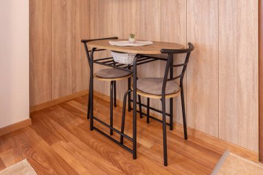 Modern iki metal sandalye ve oturma odasının içinde bitki olan küçük masa, ahşap duvar arka planı.