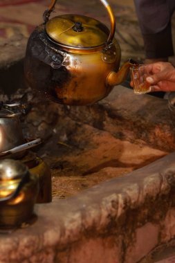 Arap Bedevisi 'nin eli çaydanlıktan geleneksel bardak Wadi Rum, Ürdün' e çay dolduruyor. Çölde kültür ve sıcak konukseverlik.