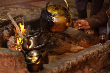 Arap Bedevisi 'nin eli çaydanlıktan geleneksel bardak Wadi Rum, Ürdün' e çay dolduruyor. Çölde kültür ve sıcak konukseverlik.