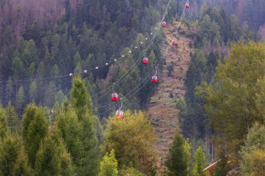 Ortisei, Italya- 26 Eylül 2024: Mont Seuc teleferik kırmızı kabinli Dolomitlerde yaz alp manzarası