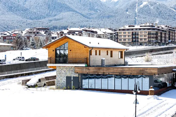 Bansko, Bulgaristan - 7 Nisan 2025: Bulgar kayak beldesinde kışın yüksek açılı cadde manzarası, evler ve Pirin karlı dağları