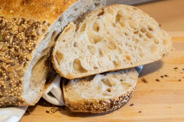 Ev yapımı taze ekmek ve mutfak masasında dilimler. Ekşi buğday ekmekli çavdar ekmeği. Tohumlar yakından görülüyor.