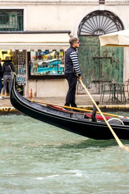 Venedik, İtalya - 30 Eylül 2024: Gondolcu eski şehrin kanalında bir gondolda