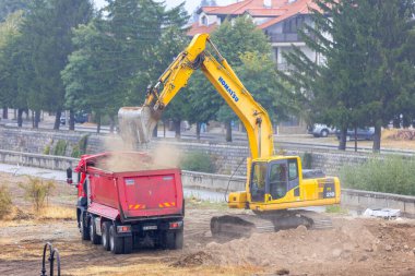 Bansko, Bulgaristan - 25 Eylül 2025: Sanayi kazıcısı bir çöp kamyonuna toprak yüklüyor