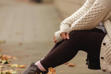 Sonbahar parkında, bej ve kahverengi renkte güzel bir kadın oturuyor.