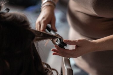 Kuaför, kuaför saç yapmak için demir aletler kullanıyor, ellere odaklanıyor.