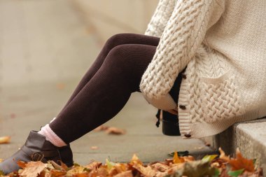 Sonbahar parkında, bej ve kahverengi renkte güzel bir kadın oturuyor.