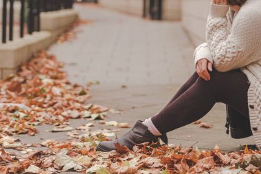 Sonbahar parkında bej ve braun renginde güzel bir kadın oturuyor.