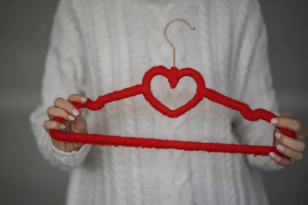 Hermosa Mujer Sosteniendo Una Percha Con Corazón Tejida Con Puntos Imagen de stock