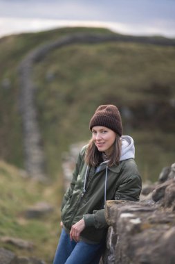 Arka planda Hadrian 'ın duvarı olan kadın turist, mutlu gezgin Northumberland, İngiltere' de seyahat ediyor. Varış ve Tatil