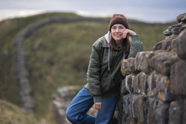 Arka planda Hadrian 'ın duvarı olan kadın turist, mutlu gezgin Northumberland, İngiltere' de seyahat ediyor. Varış ve Tatil