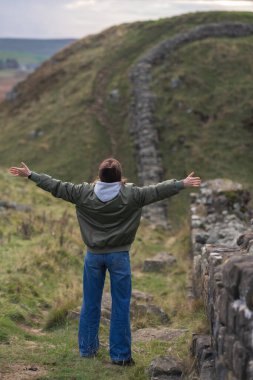 Arka planda Hadrian 'ın duvarı olan kadın turist, mutlu gezgin Northumberland, İngiltere' de seyahat ediyor. Varış ve Tatil