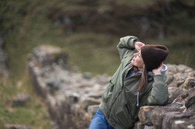 Arka planda Hadrian 'ın duvarı olan kadın turist, mutlu gezgin Northumberland, İngiltere' de seyahat ediyor. Varış ve Tatil