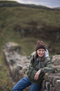 Arka planda Hadrian 'ın duvarı olan kadın turist, mutlu gezgin Northumberland, İngiltere' de seyahat ediyor..