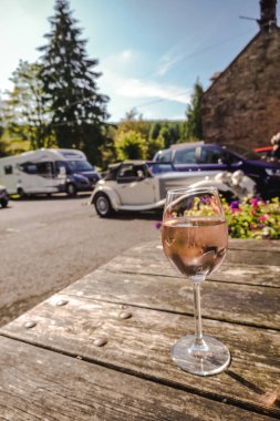 Northumberland, Birleşik Krallık - 31 Ağustos 2024: Arka planda eski arabalarla bir bardak şarap, İngiltere 'de seyahat, tatil konsepti