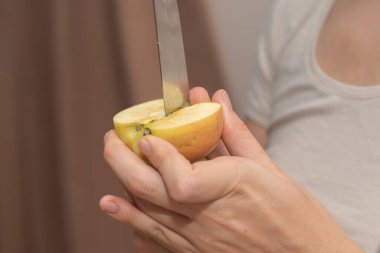 Slicing an Apple with Knife. Cutting a ripe apple in half with a kitchen knife clipart