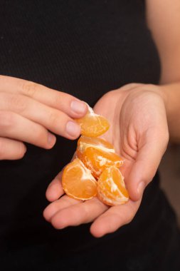 Peeling a Fresh Orange Mandarin. Female Hands skillfully peeling a juicy ripe mandarin clipart