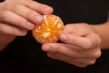 Peeling a Fresh Orange Mandarin. Female Hands skillfully peeling a juicy ripe mandarin clipart